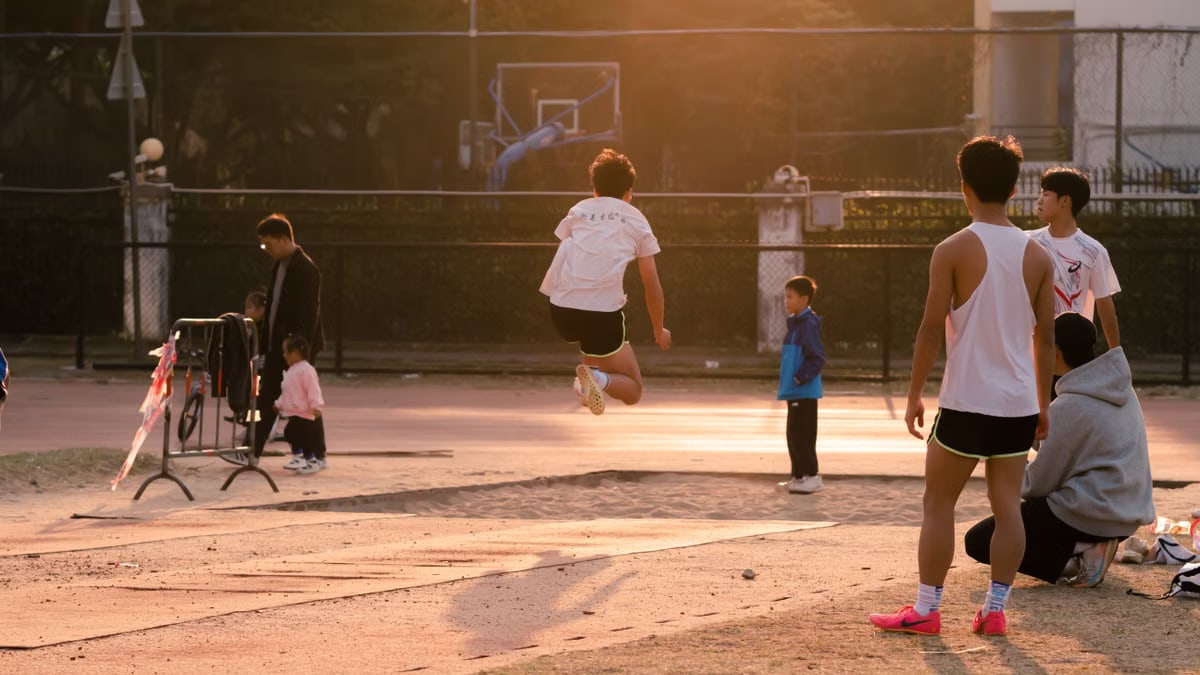 Teenagers enjoying outdoor activities in a school playground during sunset, showcasing energy and sportsmanship.